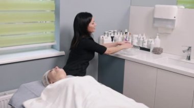 Silinmiş, maske kalıntıları, kozmetoloji prosedürü. Güzellik uzmanı, bir kozmetoloji kliniğinde müşterilerden kalan maskeyi peçeteyle siliyor.