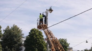 Antende teknisyen, ışığı tamir et, tamir et. Sokak lambası tamiri, tepedeki sokak lambasını tamir eden işçiler, yeni lambalar takmak, direği tamir eden işçiler.