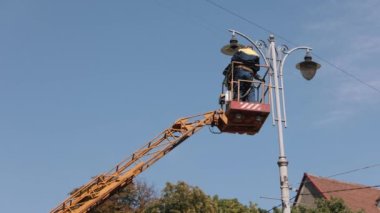 replace light bulb, Technician on aerial, during installation. Repairs are needed for street light poles. worker is climbing ladder to repair street lamp at height, changing light bulbs