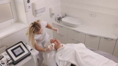 aesthetic salon, beauty center, enjoying massage. Spa concept of beauty, skin care, treatment, female with facial massage in beauty clinic, young woman lying on back, receiving facelift massage.