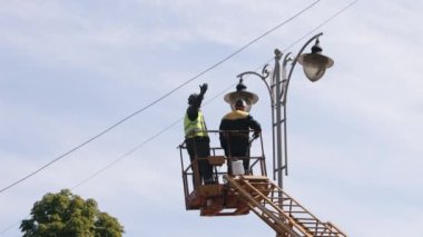 diode lights, Technician aerial, worker repair. Worker is fixing street light pole lamp at height, replacing led lights. Men wearing personal protective equipment is fixing lamp pole lamp, fixing