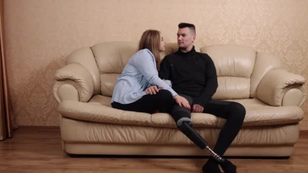 義肢の抱擁 障害のあるカップル 巨大な快適さ 義肢を持ち抱きかかえ喜びと愛を感じている夫と一緒にソファに座っている女性 — ストック動画
