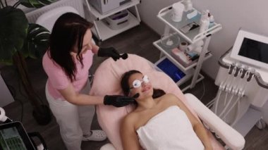 Kozmetik kliniği, spa konsepti, lazer epilasyonu. Epilasyondan önce kadın yüzüne ultrason jeli kullanan Esthetisyen kadın derisini lazer tüy aldırma tedavisi için hazırlıyor.