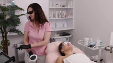 Lazer cihazı, kozmetik terapist, saç aldırma. Genç bir kadın, saç aldırma, lazer epilasyon, kozmetoloji, kozmetoloji ve spa konsepti için kaplıcada bacağına lazer tedavisi görüyor.
