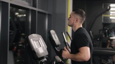 Bacak kasları, vücut kasları, koşu bandı hızı. Genç adam egzersizini koşu bandında koşarak yapıyor..
