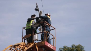 Elektrik, sokak lambası, ekipman tesisatı. İşçiler sokak lambasını onarıyor, sokak lambalarını değiştiriyor, asansör kovasında kişisel koruma takıyor.