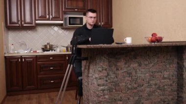 Protez bacak, adaptasyon ekipmanları, ulaşılabilir çalışma alanı. Protez bacaklı, gözlüklü, laptopta koltuk değnekleriyle çalışan bir adam..