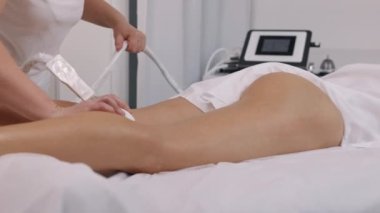 Endermologie, selülit düzeltme, tekerlekli masaj. Güzellik salonundan genç bir kadın güzellik hizmetleri sunuyor, vücut şekillendiriyor, masörler müşteriler için elektrikli süpürge masajı yapıyor, figür düzeltme yapıyor.