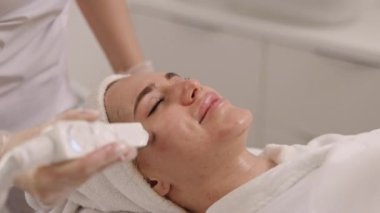 Ultra masaj, hırdavatçı kozmetolojisi, güzellik hizmetleri. Elektrikli yüz masajı güzellik elektroporasyon makinesi tarafından spa kliniğindeki genç bayana sağlanır. Kadın heyecan verici bir elektrik alıyor.