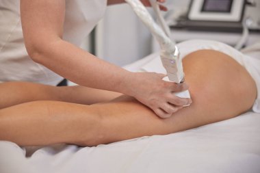 Masör, FDA onaylı, LPG masajı. Vücut şekillendirme makinesi olan genç bir kadın, masör elektrikli süpürgeyle masaj yapıyor, figür düzeltme masajı yapıyor profesyonel güzellik kliniğinde selülit karşıtı masaj yapıyor.