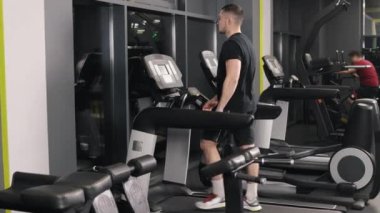 Erkek egzersizi, kardiyo çalışması, koşu rutini. Genç adam spor salonunda koşu bandında egzersiz yapıyor..