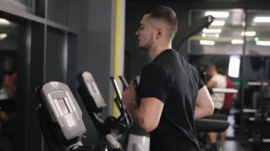 Kalp sağlığı, spor salonu koşu bandı, egzersiz alışkanlıkları. Adam spor salonunda koşu bandında koşarken terliyor..