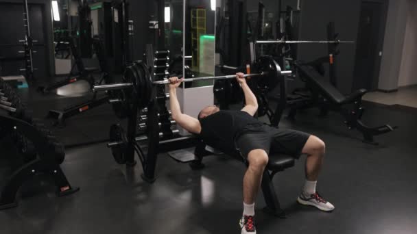 男性のボディビルダー ワークアウトの強度 重量挙げ装置 ジムには腕の筋肉を作ることに専念している若い男性のボディービルがあります — ストック動画