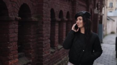 Yayalar, kadın konuşmaları, şehir gezginleri. Genç bir kadın kaldırımdan aşağı inerken telefonla konuşuyor..