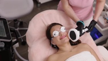 Güzellik merkezi, kadın yüzü, saç kesimi. Genç kadının bacağına lazer tedavisi uygulanırken lazer epilasyon, kozmetoloji, kozmetoloji ve lazer kullanılarak tüy çıkarma prosedürleri uygulanır.