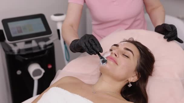 軟膏のアプリケーション 顔の治療 美容業界 美容師は女性患者の顔に白いクリーム軟膏を広げます — ストック動画