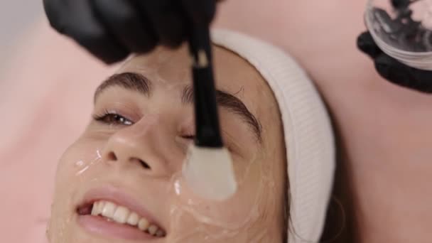 手術以外のリフティング 美容専門家 Rfフェイスリフト 美容師はRfリフティング手順の準備でナックルを持つ患者の皮膚に導電性ゲルを適用します — ストック動画