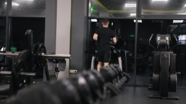 Koşu ayakkabıları, spor salonu kültürü, koşu bandı. Genç adam dayanıklılığını koşu bandında koşarak kazanıyor..