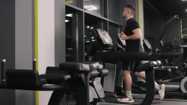 フィットネス目標 筋力トレーニング ジムトレッドミル ジムのメンバーは彼のトレーニングのためにトレッドミルで走っています — ストック動画