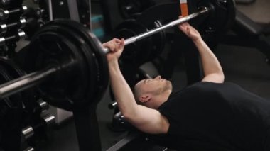 Halter egzersizi, egzersiz, makine döşeme. Vücut geliştirici fitness hedefleri için ağırlık kaldırırken metal şıngırtıları duyulabiliyor..