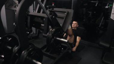 Spor hocası, sağlıklı bir yaşam tarzı var. Sporcu kas kütlesi geliştirmek için bacak egzersizi makinesi kullanır.