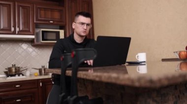Taşınabilirlik yardımı, protez bacak, dizüstü bilgisayar işi. Bacak protezi ve gözlüklü bir adam dizüstü bilgisayarda çalışıyor, koltuk değneklerini kullanabiliyor..