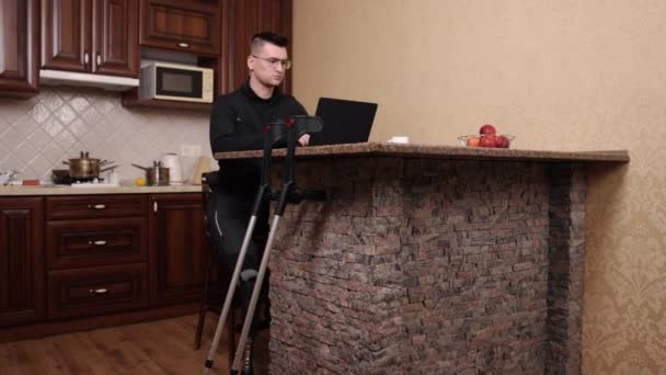 アンプテーコンピュータ支援技術ワークステーションのセットアップ 義肢と眼鏡の男はラップトップを使用しています 近い内に松葉杖 — ストック動画