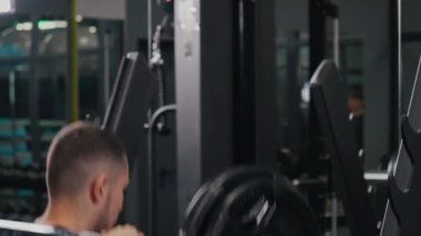 Vücut geliştirici özveri, fitness bağlılığı, alt vücut. Vücut geliştirici ağırlıklı halter çömelmeleri yaparak güçlü bir erkeklik örneği sergiliyor, sağlık ve zindeliğe bağlılığı vurguluyor..