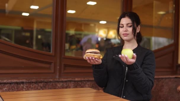 アップルの選択 食糧優先 バーガーの解雇 女性はハンバーガーのようなファーストフードにふけるのではなく アップルを食べることにしました — ストック動画