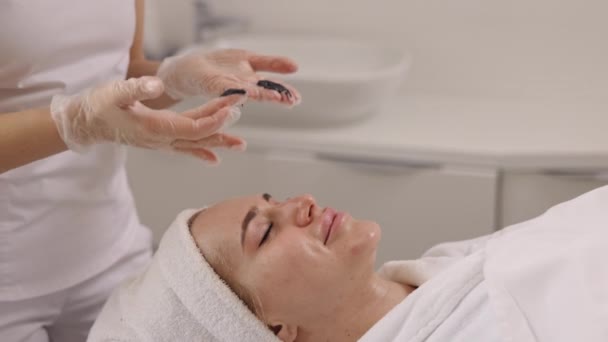 Skönhetssalong Ansiktsavgiftning Lerterapi Skönhetssalong Kosmetolog Administrerar Svart Mask Klienter Ansikte — Stockvideo