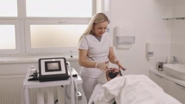 Asansör tedavisi, sivilcelerle mücadele, deri dökülmesi. Güzellik salonu dekorasyonu, kozmetolog müşterilerin yüzüne siyah maske takıyor, yüz temizleme, kaldırma, yosun bazlı gençleştirme, çamur terapisi.