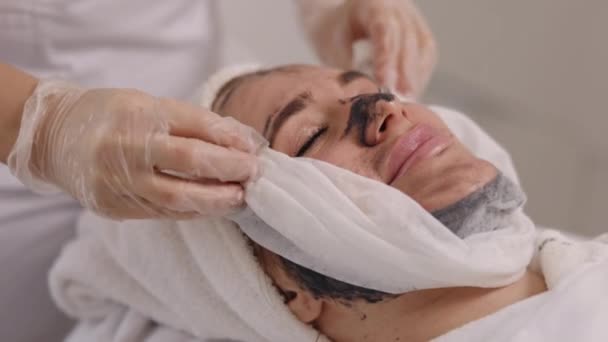 Schönheitssalon Gesichtsbehandlung Schlammtherapie Mit Serviette Hautpflege Spezialist Trägt Schwarze Maske — Stockvideo