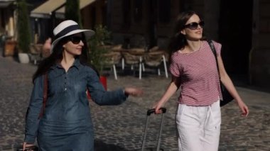 Gülümseyen Genç, Tatil Tatili, Bagaj Keşfi. İki güzel kadın kaşif bulvarda avare avare dolaşıyorlar bavullarını kapıp uluslararası maceralarının tadını çıkarıyorlar..