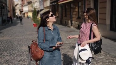 Yol göster, bayan gezgin, bir yolunu bul. Seyahat konsepti, elektronik tablet haritasında yollarını arayan iki kadın gezgin tarafından somutlaştırılmıştır..