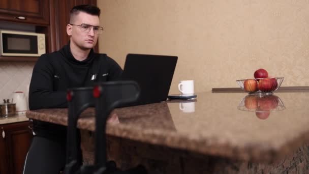适应残疾 工作场所便利 辅助工具 带着假腿和眼镜的人在笔记本电脑上工作 身边有拐杖 — 图库视频影像