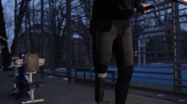 Rehabilitasyon egzersizi, protez bacak, aktif yaşam tarzı. Spor sahasında düzensiz barfiks çekerek egzersiz yapma eylemi protez bacaklı engelli bir adam tarafından gerçekleştiriliyor..
