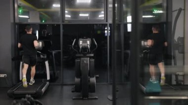 Antrenman, spor salonu takip cihazı, koşu bandı. Adam fitness hedeflerine ulaşmak için koşu bandı kullanıyor..