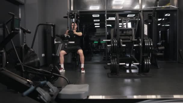 ワークアウトマシンダンベルワークアウト筋肉 ハンサムな 物理的にフィット男はフィットネスセンターで運動機械を使用して腕や胸の筋肉を構築することに取り組んでいます — ストック動画