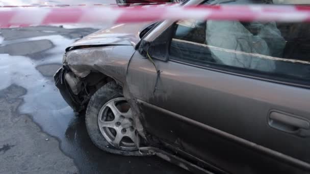 自動車事故衝突事故車のバリアー 衝突でフロントエンドがひどく損傷した状態で ハザードテープでフェンスで囲まれた車 — ストック動画