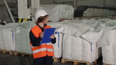 Depo, Beyaz Torbalar, Mal Denetleme 'de tarım. Endüstriyel alanda, kadın müfettiş malları değerlendirir, beyaz çuvalları sayar ve gözlemlerini kaydeder..