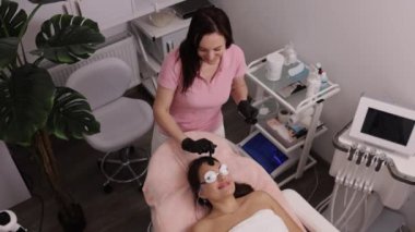 Jöle, tek kullanımlık spatula, lazer epilasyonu. Kadın yüzüne epilasyon yapılmadan önce ultrason jeli uygulayan kozmetikçi, kadın derisini lazer tüy aldırmaya hazırlayan Esthetisyen kadın epilasyonu