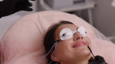 Güzellik salonu, jel sürme, lazer epilasyon. Epilasyondan önce kadın yüzüne ultrason jeli kullanan Esthetisyen kadın derisini lazer tüy aldırma tedavisi için hazırlıyor.