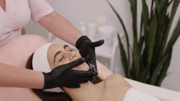 肌肤按摩 护肤面膜 镇静护肤 美容师使用舒缓的面霜 轻轻抹在皮肤上 然后在病人身上戴上口罩 — 图库视频影像