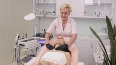 Deri temizleme, etkili temizlik, müşteri bakımı. Güzellik uzmanı temizleme çözeltisi ile ıslatılmış bez kullanarak hastaların cildindeki kirliliği dikkatlice temizler..