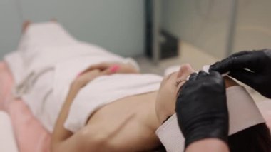 Yüz bakımı, pamuk temizleme, nemlendirici sis. Estetikçi yüzü pamuk pedlerle sulandırır..