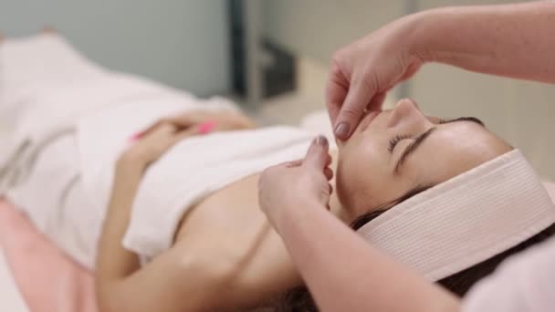 放松按摩 补肾疗法 皮肤更新 女性美容师在进行面部按摩时 会在病人脸上抹上护肤霜 — 图库视频影像