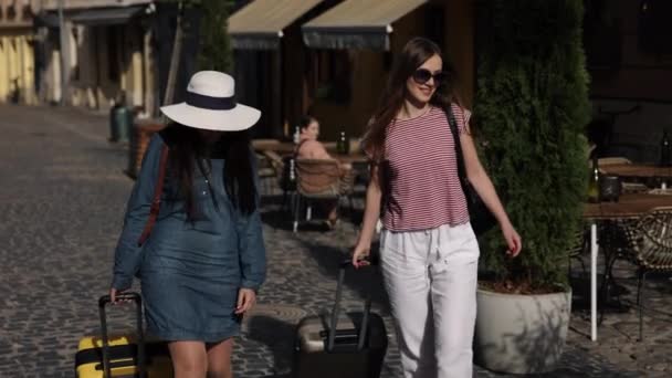 女性朋友 两个朋友 出国旅行 两个有吸引力的女度假者手握手提箱 在大街上蹒跚而行 沉浸在国外旅行的欢乐之中 — 图库视频影像