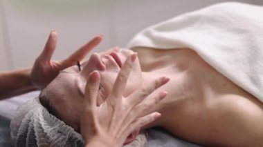 Kozmetik dermatoloji, güzellik salonu, kozmetoloji tedavisi. Kadın olan cilt bakıcısı hastaların yüzüne SPF güneş kremi sürmüş.