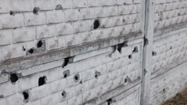 Mermi delik deşik olmuş, bombardımandan sonra, delinmiş duvar. Ukrayna savaşı, savaş sırasında yok edilen kurşun delikleriyle beton çitleri ya da bombardıman toplarını yok etti.