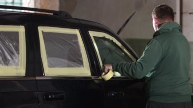 Kapsama prosedürü, onarım süreci, gerekli malzemeler. Tamirci, düzgün boya yapabilmek için arabayı kağıda sarar..